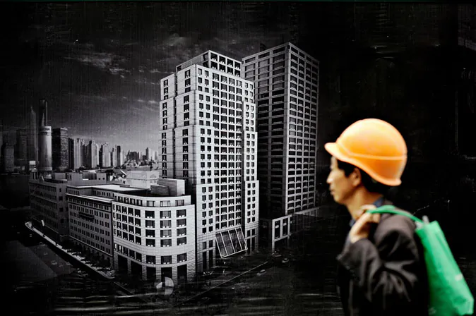A worker walks past a billboard advertising a new real estate project in Shanghai.  (Philippe Lopez/AFP/Getty Images)