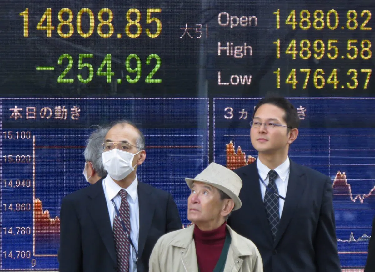 Pedestrians stand in front of a share price board in Tokyo on April 7, 2014. (Kazuhiro Nogi/AFP/Getty Images)