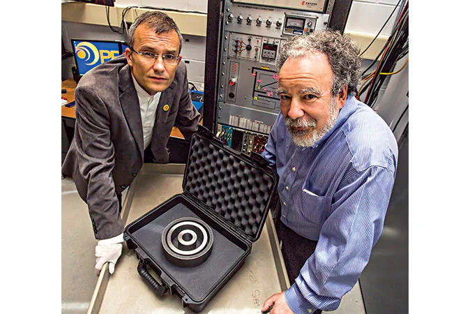 Physicists Alexander Glaser, left, and Robert Goldston display the non-nuclear test object that will serve as a target in their research. (Elle Starkman/Princeton Plasma Physics Laboratory)