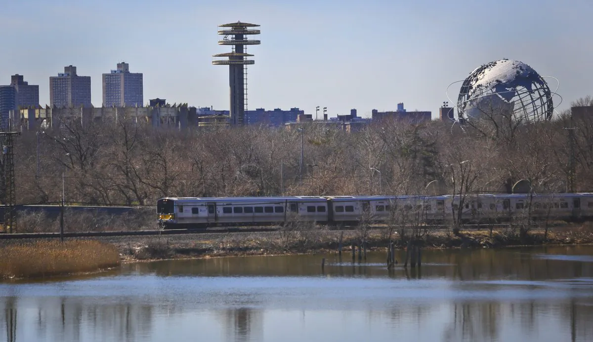 A space-age tower, left, and a giant metal globe called the Unisphere, right, structures remaining from the 1964 World's Fair, looms above a passing LIRR train on Tuesday April 1, 2014 in the Queens borough of New York.  As this month’s 50th anniversary of the 1964 New York World’s Fair approaches, a debate has emerged about what to do with some of the fair’s most famous structures. The towers topped by flying-saucer-like platforms, and a pavilion of pillars once called the “Tent of Tomorrow,” still sit as abandoned relics in the middle of Queens' Flushing Meadows Corona Park.   (AP Photo/Bebeto Matthews)