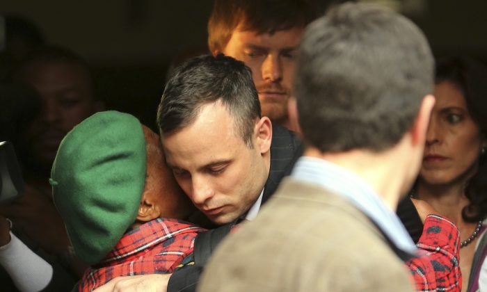 Oscar Pistorius, center, shares a hug with an unidentified woman as he leaves the high court in Pretoria, South Africa, Wednesday, April 16, 2014. Pistorius is charged with murder for the shooting death of his girlfriend, Reeva Steenkamp, on Valentines Day in 2013. (AP Photo/Themba Hadebe)