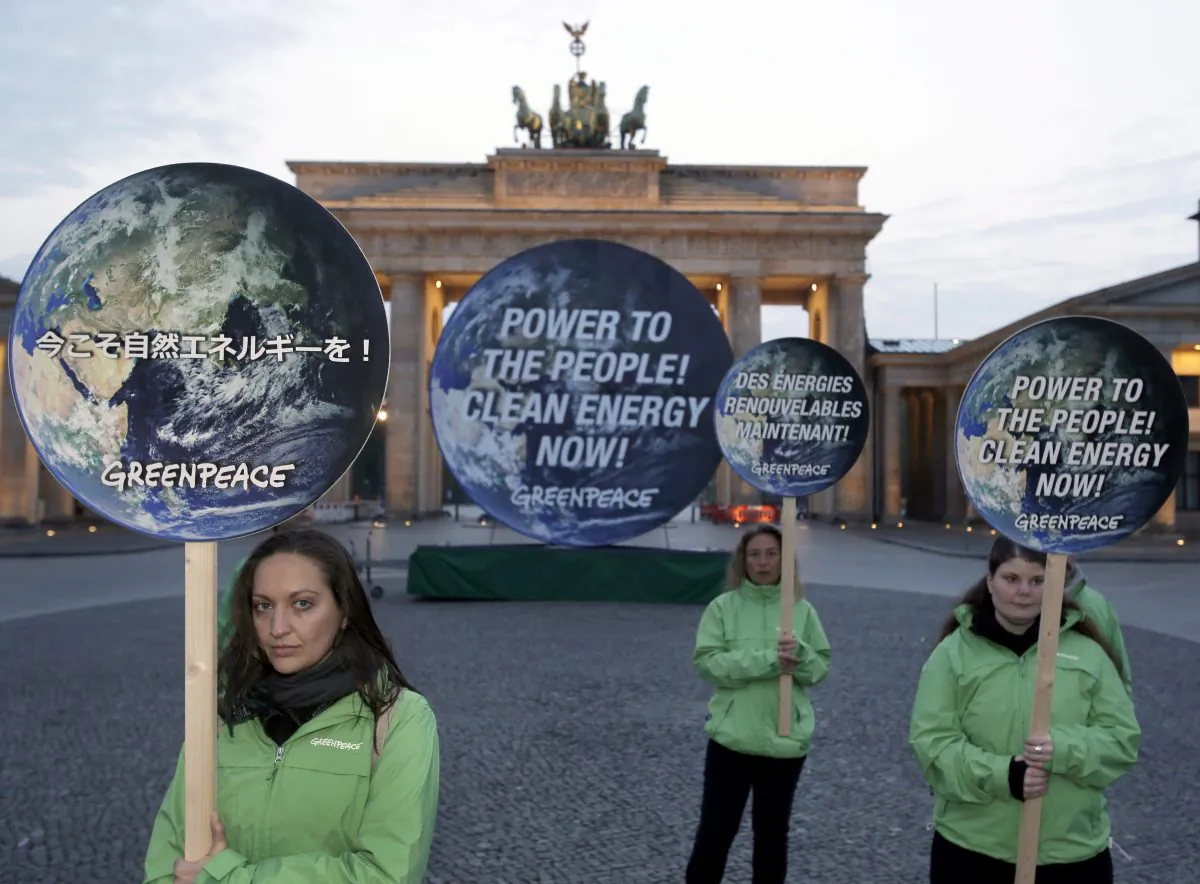 Greenpeace activists pose with posters in front of the Brandenburg Gate in Berlin, Germany, on April 13, 2014 to support clean energy. A Canadian study analyzing temperature data since 1500 all but rules out the possibility that global warming in the industrial era is just a natural fluctuation in the earth’s climate. (AP Photo/Michael Sohn)