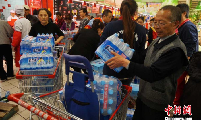Citizens carry bottled water out of a supermarket in Lanzhou, northwest China's Gansu Province, on April 11, 2014, after tap water in a Lanzhou was found to contain excessive levels of the toxic chemical benzene. (STR/AFP/Getty Images)