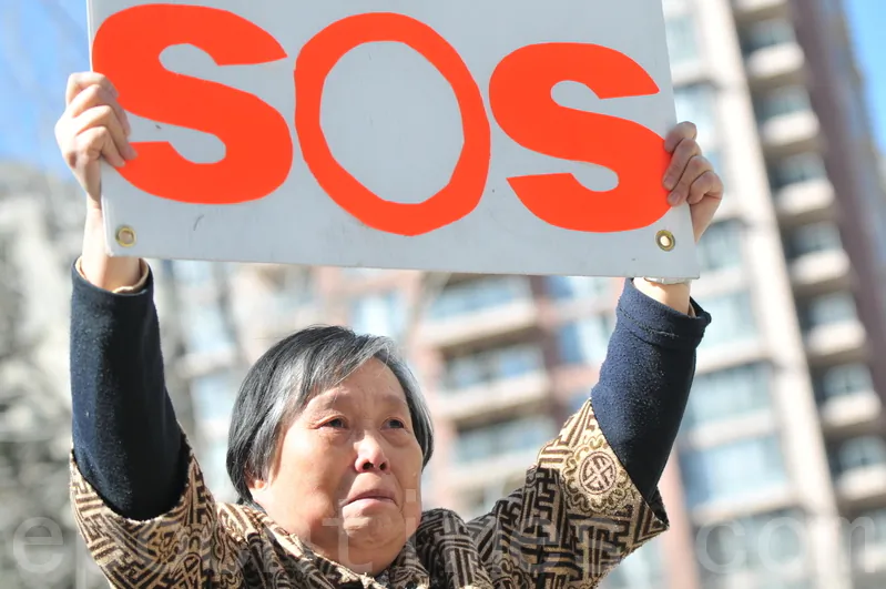 Huang Jinling holds an SOS sign at a press conference in Calgary on April 15, 2014 calling for help to rescue her daughter Chen Yinghua from a detention centre in China where she is said to be near death from a hunger strike. (Wu Weilin/Epoch Times)