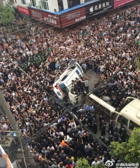 The angry crowd turns an ambulance on its side in Wenzhou City of Zhejiang Province on April 19. Over 1,000 people besieged five chengguan officers after they assaulted an onlooker. (Weibo)