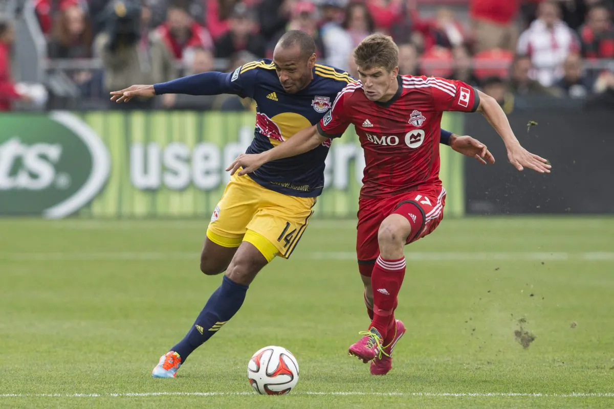 New York’s Thierry Henry competes for the ball with Toronto’s Nick Hagglund in MLS action on May 17, 2014 in Toronto. (Chris Young/The Canadian Press)