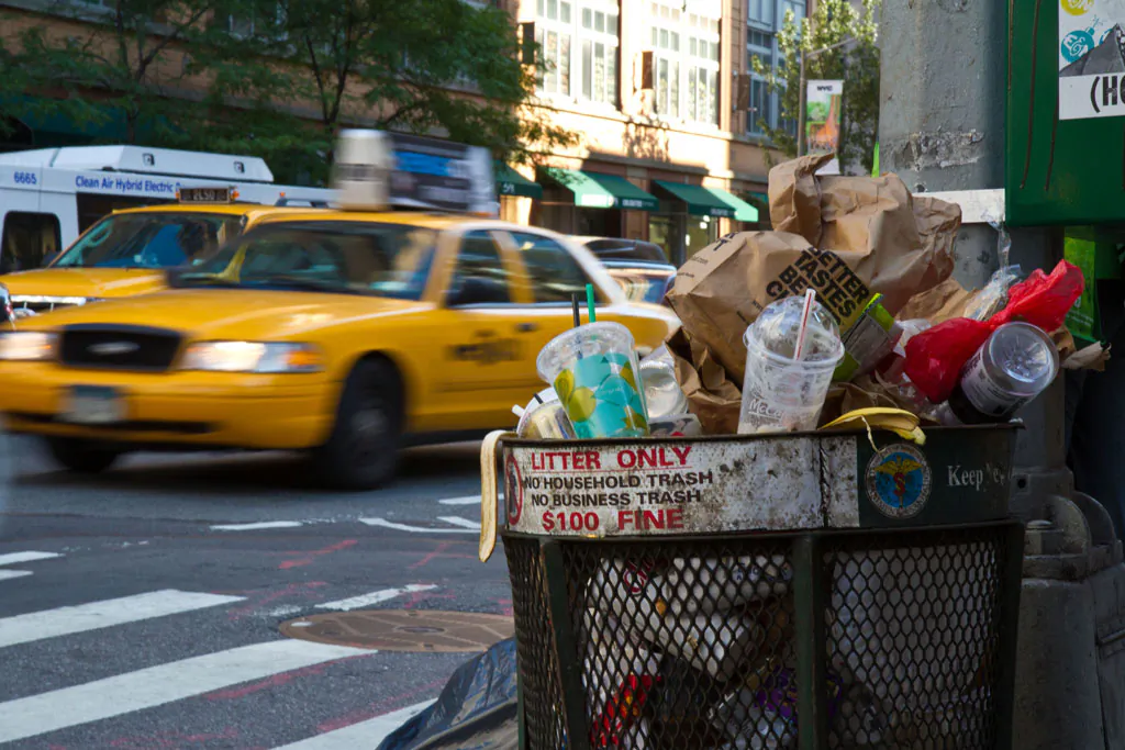 A trash can full of garbage is on Sixth Avenue right before it was emptied by a sanitation truck, in New York City, in this file photo. (Benjamin Chasteen/Epoch Times)