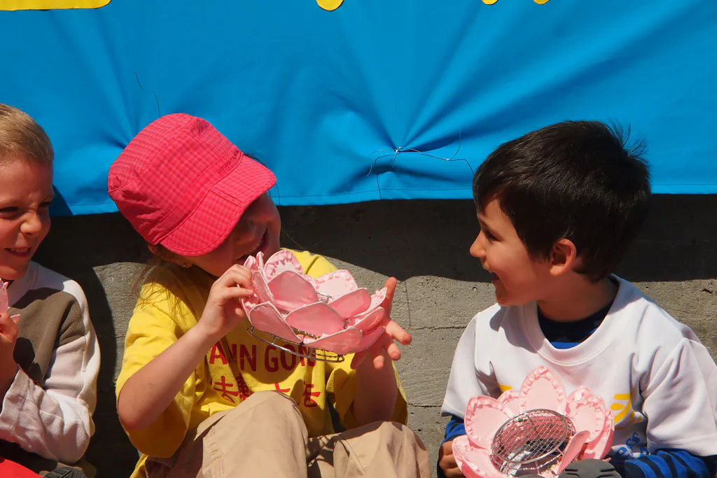 Young Falun Gong practitioners play with a lotus flower that they are handing out to passersby. On May 10, 2014 Falun Gong practitioners in Montreal commemorated Falun Dafa Day. (Epoch Times)