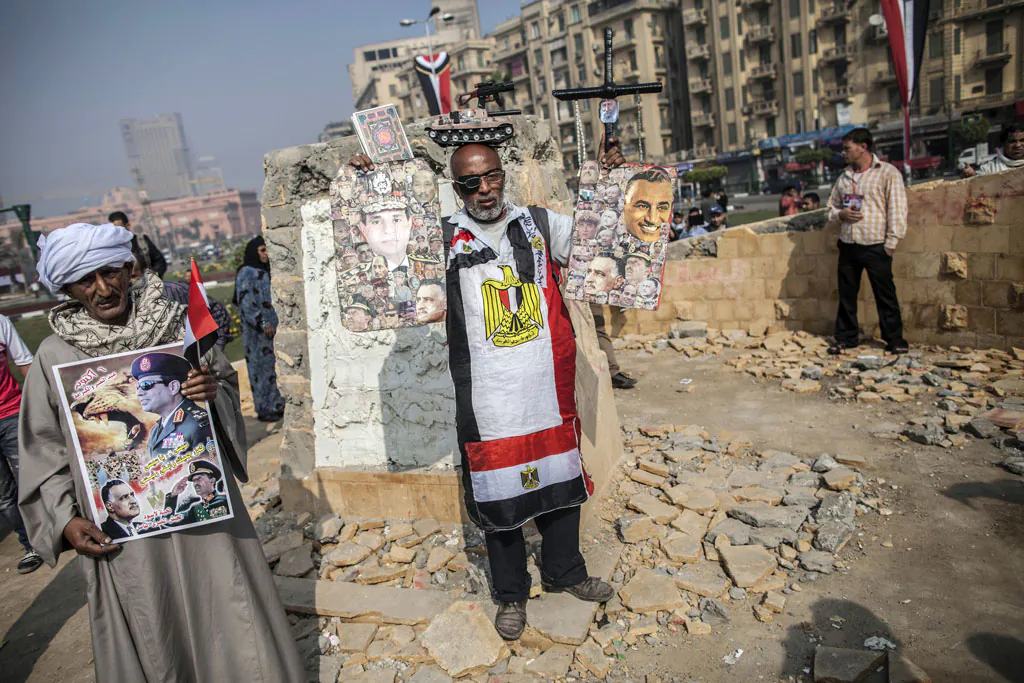 An Egyptian man dressed in the colours of his national flag and holding posters bearing images of Egypt's Defense Minister General Abdel-Fattah el-Sissi (L) and late Egyptian president Gamal Abdel Nasser (L) amongst other political leaders as protestors gather in Tahrir square to mark the anniversary of anti-military protests on November 19, 2013 in Cairo. Dozens of supporters and opponents of the army gathered in Tahrir to mark the anniversary of anti-military protests, amid mounting anger over a memorial to those killed in Egypt's uprising. (Mahmoud Khaled/AFP/Getty Images)