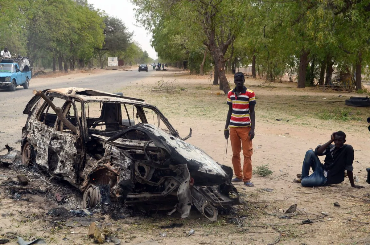 People stand by the wreckage of a car that has been blown up by suspected Boko Haram militants in Nigeria's troubled northeastern city of Maiduguri on March 25, 2014. (AFP/Getty Images)
