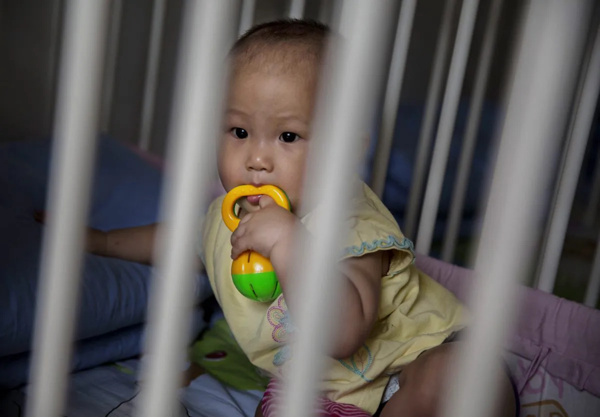 A young orphaned Chinese girl sits in a crib at a foster care center in Beijing, China, on April 2, 2014. (Kevin Frayer/Getty Images)