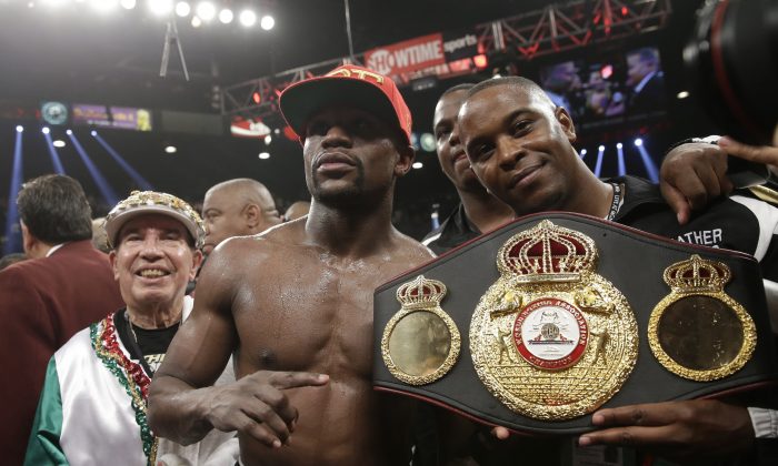 Floyd Mayweather Jr., center, poses with his corner and a champion's belt after his WBC-WBA welterweight title boxing fight against Marcos Maidana Saturday, May 3, 2014, in Las Vegas. Mayweather won the bout by majority decision. (AP Photo/Isaac Brekken)