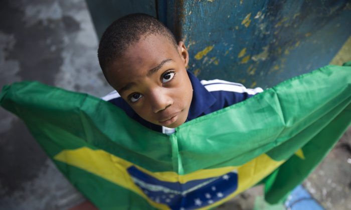 A boy holds a representation of Brazil's national flag during a protest against public money spent on the preparations for the 2014 World Cup, at the Jacarezinho slum, in Rio de Janeiro, Brazil, on May 10, 2014. (AP Photo/Hassan Ammar)