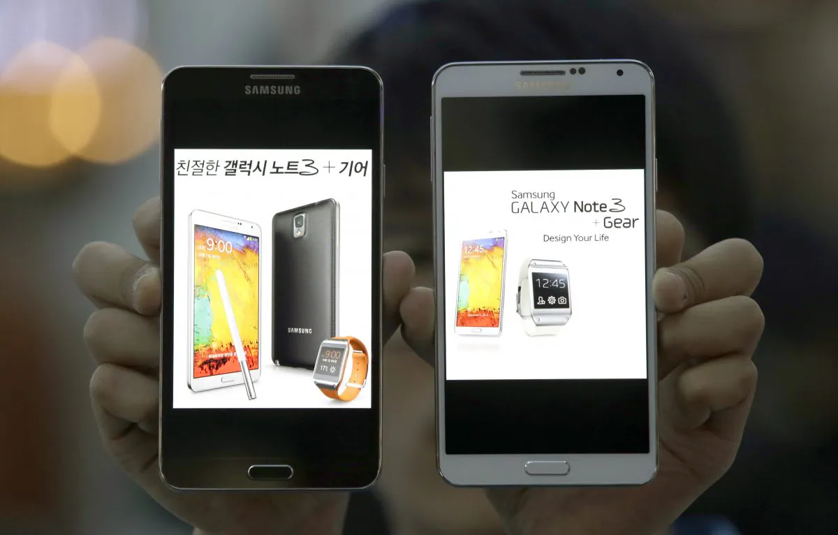 An employee of Samsung Electronics holds two Galaxy Note 3 smartphones for photos at a train station in Seoul, South Korea, Wednesday, Oct. 23, 2013. (AP Photo/Lee Jin-man)