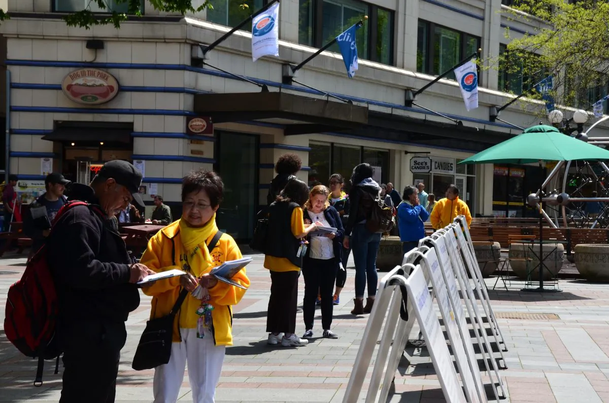 A passerby signs a petition calling on members of the U.S. Congress to co-sponsor House Resolution 281, which calls for an end of forced organ harvesting in China, in Westlake Park in downtown Seattle, Washington on May 11, 2014. (Epoch Times)