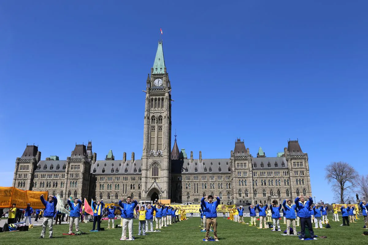 Falun Dafa practitioners from Montreal, Ottawa, and Toronto on Parliament Hill in Ottawa, Canada, to celebrate World Falun Dafa Day demonstrate the exercises that are a daily part of the practice, May 7, 2014. (Donna He/Epoch Times)