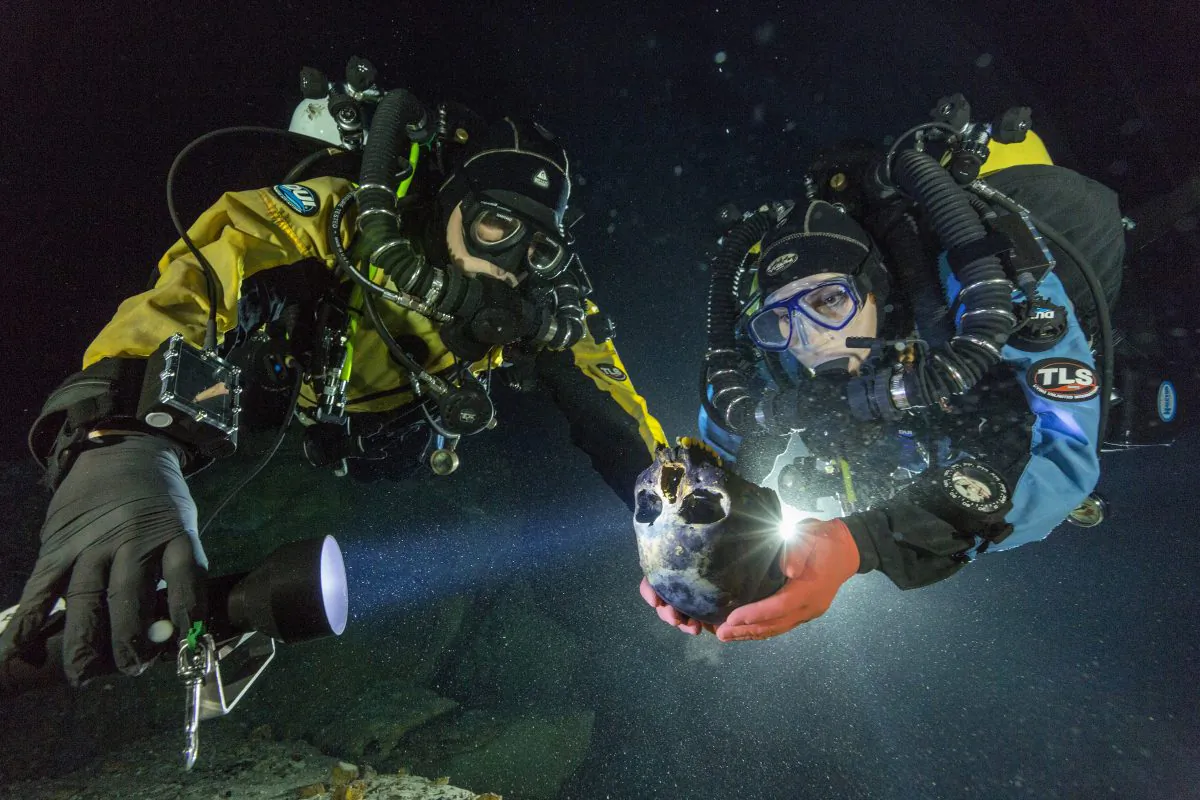 In this June 2013 photo provided by National Geographic, divers Alberto Nava and Susan Bird transport the Hoyo Negro skull to an underwater turntable so that it can be photographed to create a 3-D model in an underwater cave in Mexico's Yucatan Peninsula. Thousands of years ago, a teenage girl fell into this deep hole and died. Now, her skeleton and her DNA are helping scientists study the origins of the first Americans. An analysis of her remains was released Thursday, May 15, 2014 by the journal Science. Her DNA links her to an ancient land bridge connecting Asia and North America, and suggests she shares ancestors with the modern native peoples of the Americas. (AP Photo/National Geographic, Paul Nicklen)