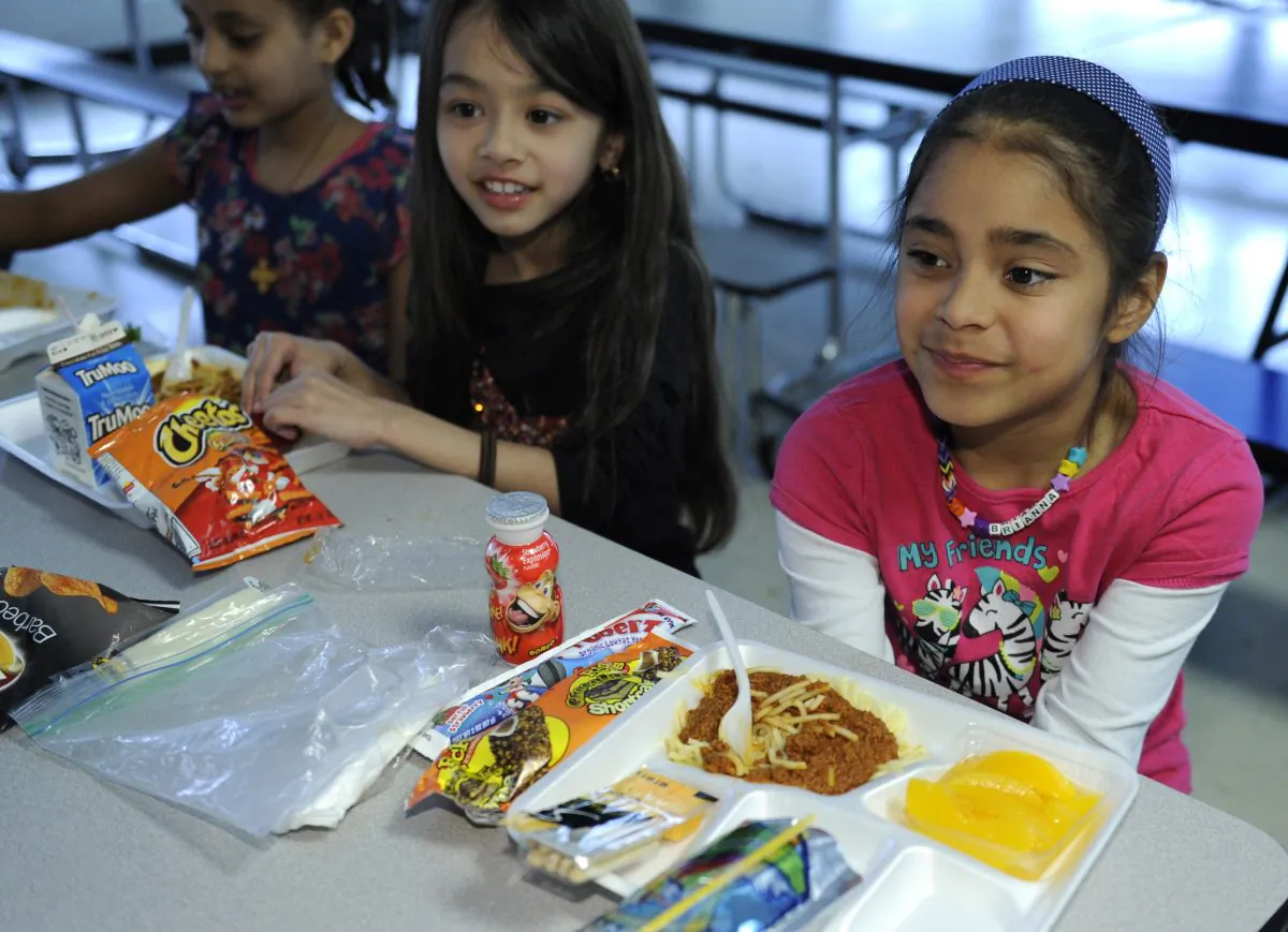 (L–R) Ruth Gebregiorgis, 8, Amina Sharif, 7, and Brianna Delcid-Gomez, 7, eat lunch at the Patrick Henry Elementary School in Alexandria, Va., April 29. (AP Photo/Susan Walsh)