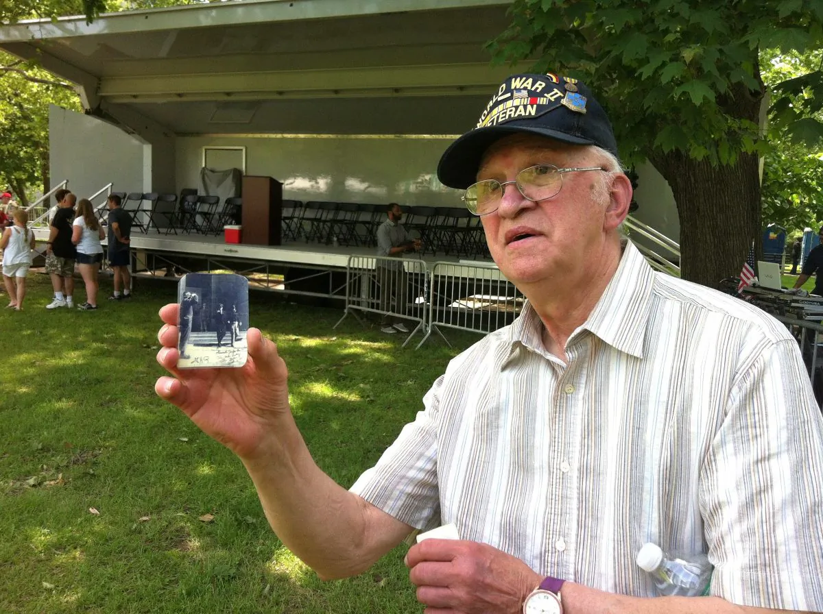 Veteran Jack Vanasco shows a picture of himself next to General Douglas MacArthur during World War II. (Sarah Le/Epoch Times)