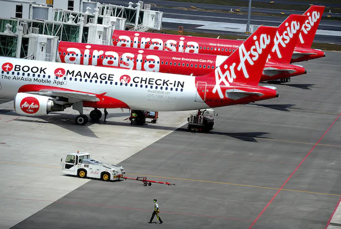 A ground crew man walks past a fleet of AirAsia's passenger jets on the tarmac of the new low cost terminal KLIA2 in Sepang, Malaysia, Friday, May 9, 2014. AirAsia on Friday began its full operations from KLIA2. (AP Photo/Joshua Paul)