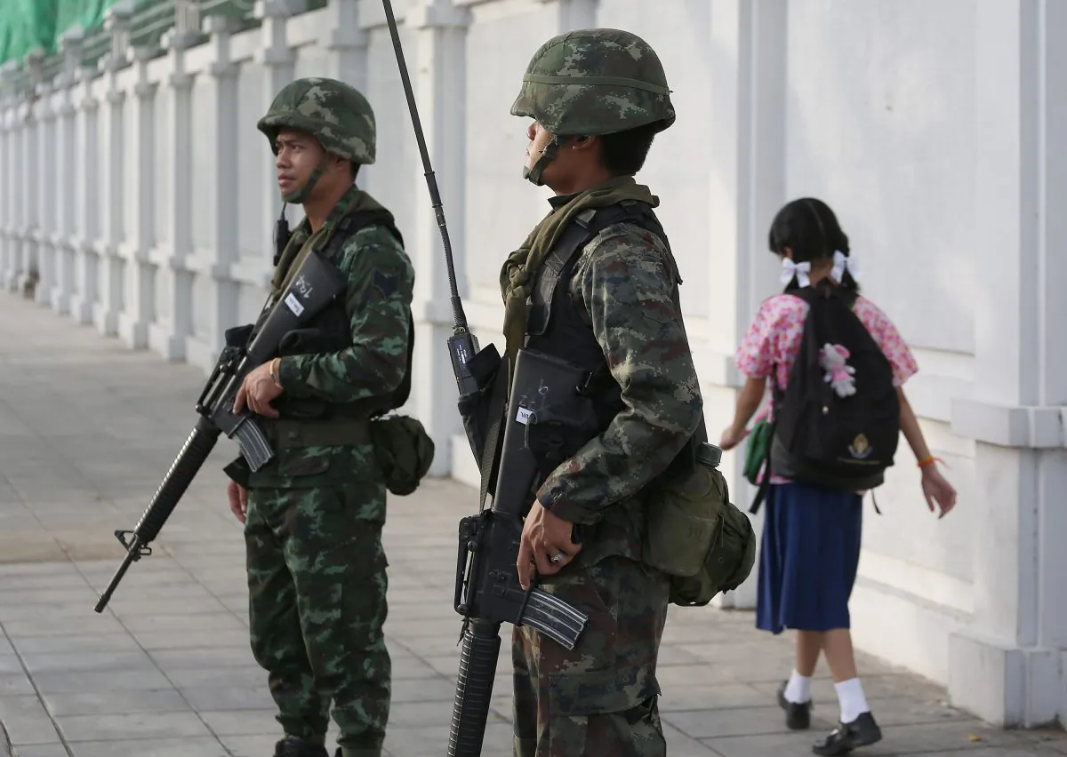 A school girl makes her way past Thai soldiers guarding at a street corner in Bangkok, Thailand Friday, May 30, 2014. (AP Photo/Apichart Weerawong)