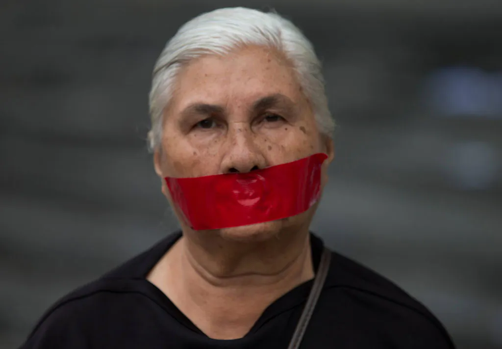 A woman with tape over her mouth in protest of officials breaking up protesters' camps, stands outside the United Nations headquarters in Caracas, Venezuela, Thursday, May 8, 2014. Hundreds of security forces broke up four camps maintained by student protesters, arresting 243 people in a Thursday pre-dawn raid. (AP Photo/Fernando Llano)