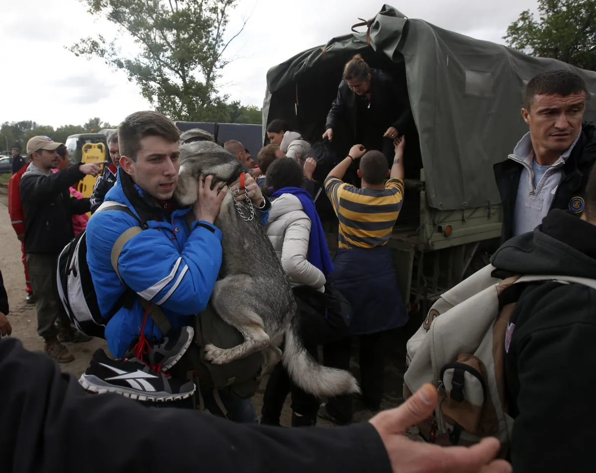 A man holds his dog during the evacuation from floods in Obrenovac, some 30 kilometers (18 miles) southwest of Belgrade Serbia, Saturday, May 17, 2014. Record flooding in the Balkans leaves at least 20 people dead in Serbia and Bosnia and is forcing tens of thousands to flee their homes. Meteorologists say the flooding is the worst since records began 120 years ago. (AP Photo/Darko Vojinovic)