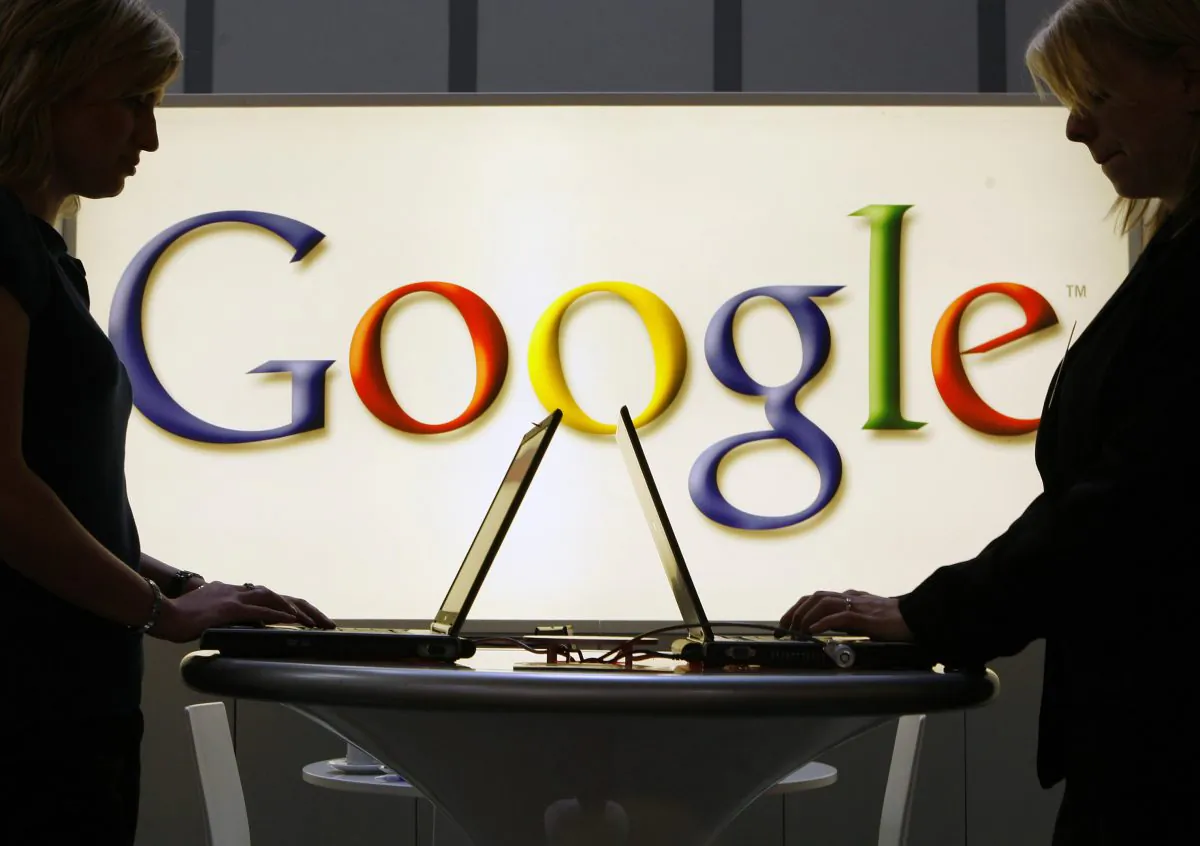 In this April 17, 2007 file photo, exhibitors of the Google company work on laptop computers in front of an illuminated sign of the Google logo at the industrial fair Hannover Messe in Hanover, Germany. (Jens Meyer/AP Photo)