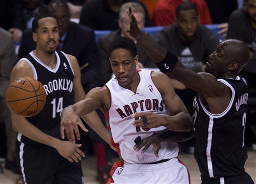 Toronto Raptors guard DeMar DeRozan, center, moves the ball past Brooklyn Nets forward Kevin Garnett, right, and Shaun Livingston (14) during the second half of Game 5 of the opening-round NBA basketball playoff series in Toronto, Wednesday, April 30, 2014. (AP Photo/The Canadian Press, Nathan Denette)