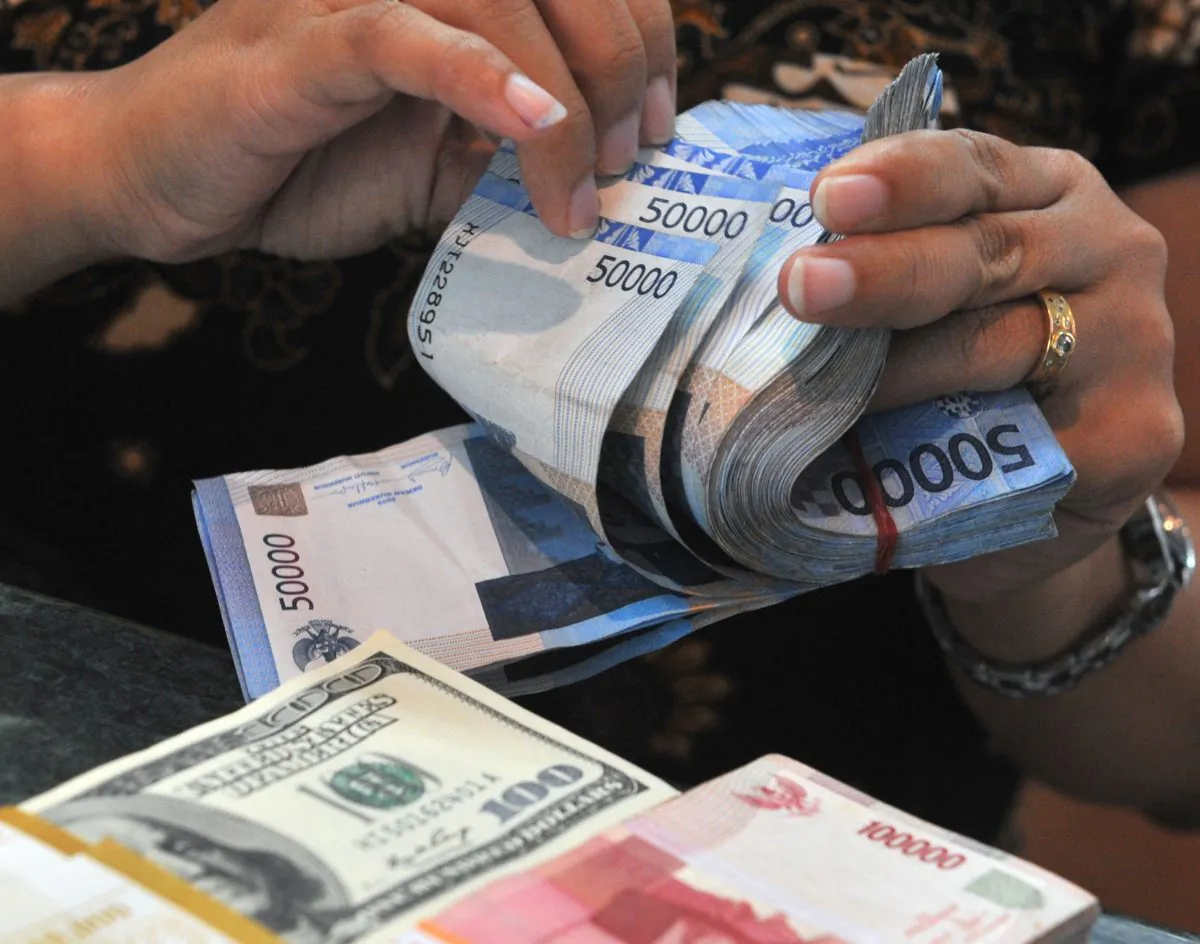 A money exchange teller counts rupiah and U.S. dollar notes in Jakarta, Indonesia, on Oct. 21, 2010. (Bay Ismoyo/AFP/Getty Images)