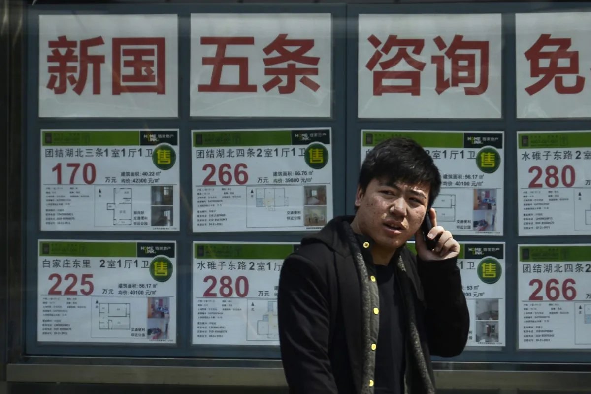 A Chinese man talks on a mobile phone in front of a real estate agency in Beijing on April 15, 2013. (Wang Zhao/AFP/Getty Images)
