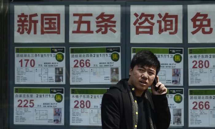 A Chinese man talks on a mobile phone in front of a real estate agency in Beijing on April 15, 2013. (Wang Zhao/AFP/Getty Images)