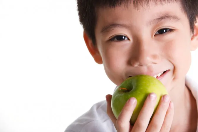 Boy eats an apple. Apples contain the most pesticide residues, according to the Environmental Working Group (EWS).