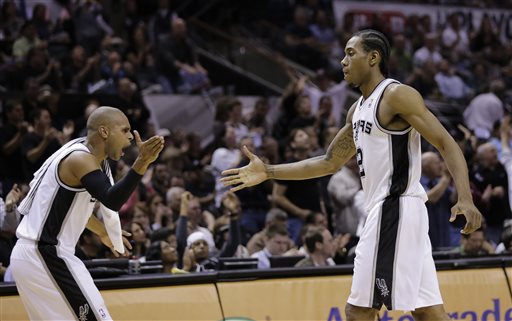 San Antonio Spurs' Patty Mills, left, slaps hands with Kawhi Leonard as Leonard walks off the court during the first half of Game 5 of a Western Conference semifinal NBA basketball playoff series against the Portland Trail Blazers, Wednesday, May 14, 2014, in San Antonio. (AP Photo/Eric Gay)