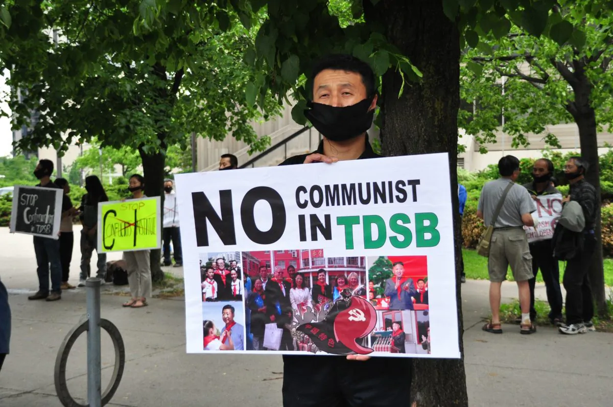 A demonstrator holds a sign to protest the Toronto District School Board's partnership with the Confucius Institute outside of the TDSB on June 11, 2014. (Allen Zhou/Epoch Times)