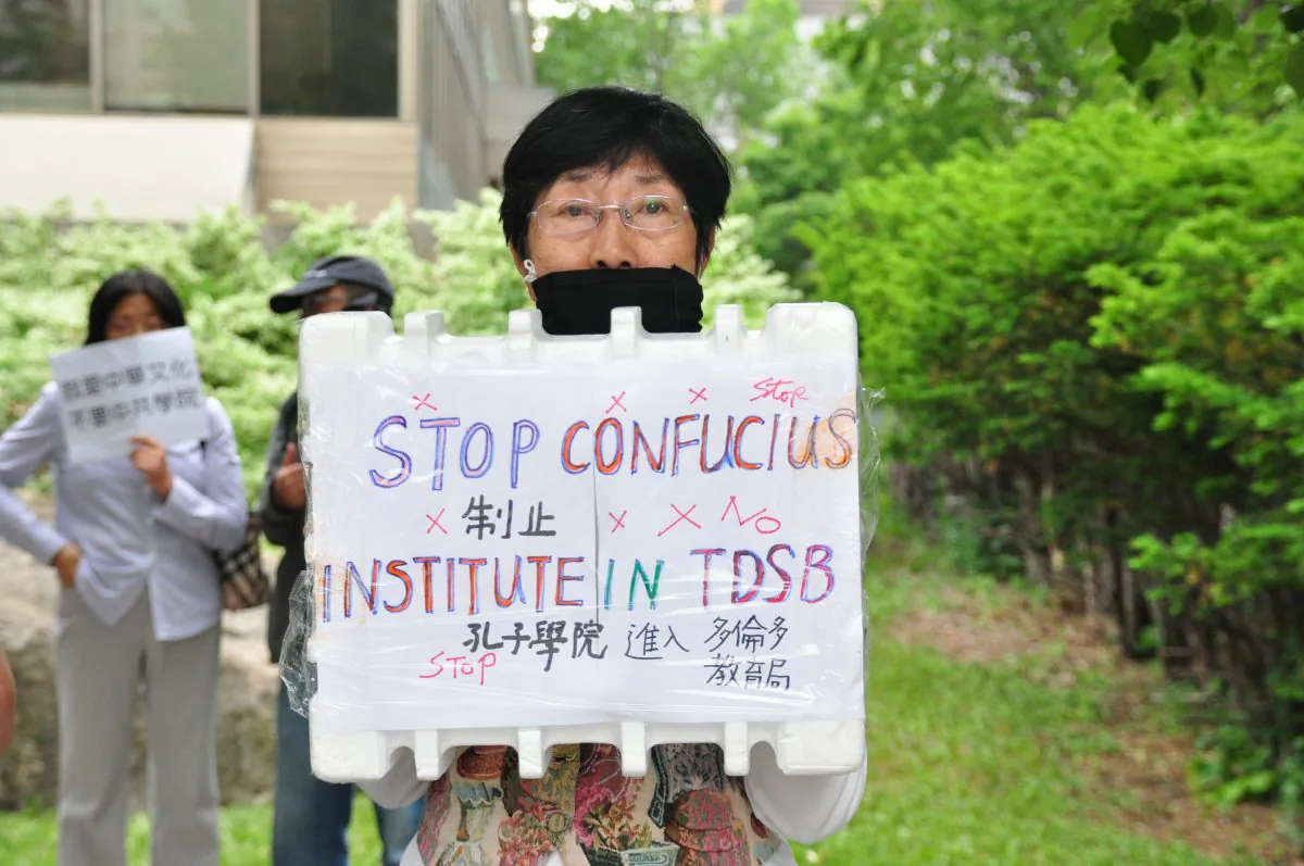 A demonstrator holds a sign to protest the Toronto District School Board's partnership with the Confucius Institute outside of the TDSB on June 11, 2014. (Allen Zhou/Epoch Times) 