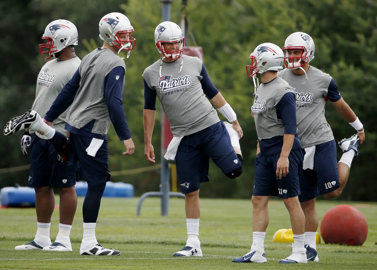 New England Patriots quarterback Tom Brady, center, stretches with teammates quarterback Ryan Mallett, second from left, wide receiver Julian Edelman (11) and quarterback Jimmy Garoppolo (10) during NFL football minicamp in Foxborough, Mass., Wednesday, June 18, 2014. (AP Photo/Michael Dwyer)