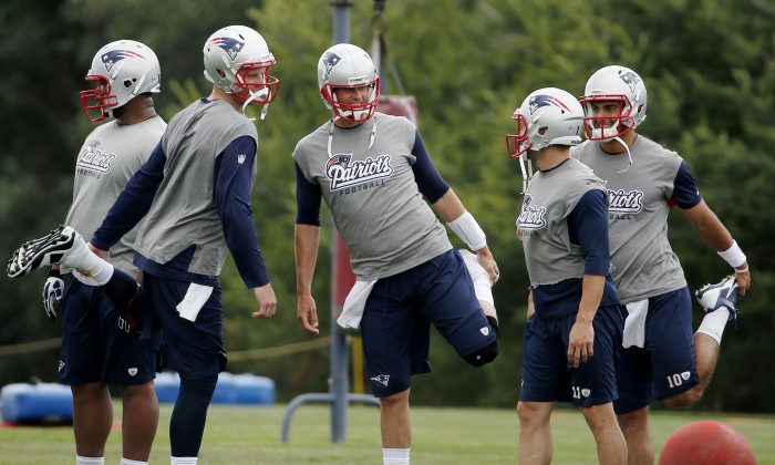 New England Patriots quarterback Tom Brady, center, stretches with teammates quarterback Ryan Mallett, second from left, wide receiver Julian Edelman (11) and quarterback Jimmy Garoppolo (10) during NFL football minicamp in Foxborough, Mass., Wednesday, June 18, 2014. (AP Photo/Michael Dwyer)