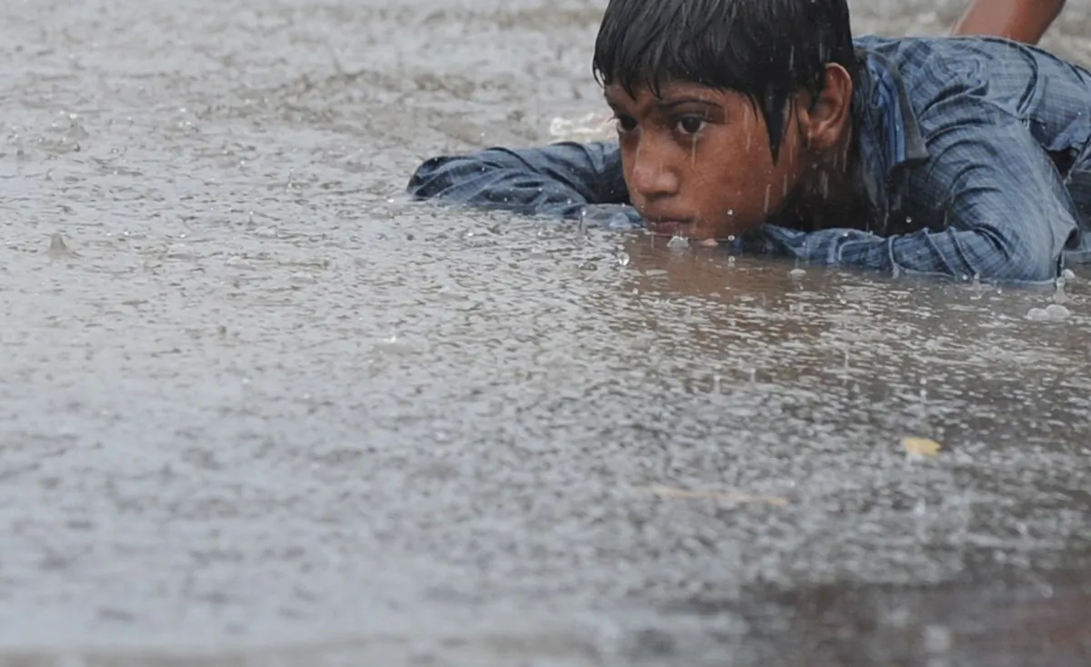 An Indian street child lies on a puddle of water along a road in New Delhi on June 16, 2013. (Sajjad Hussain/AFP/Getty Images)