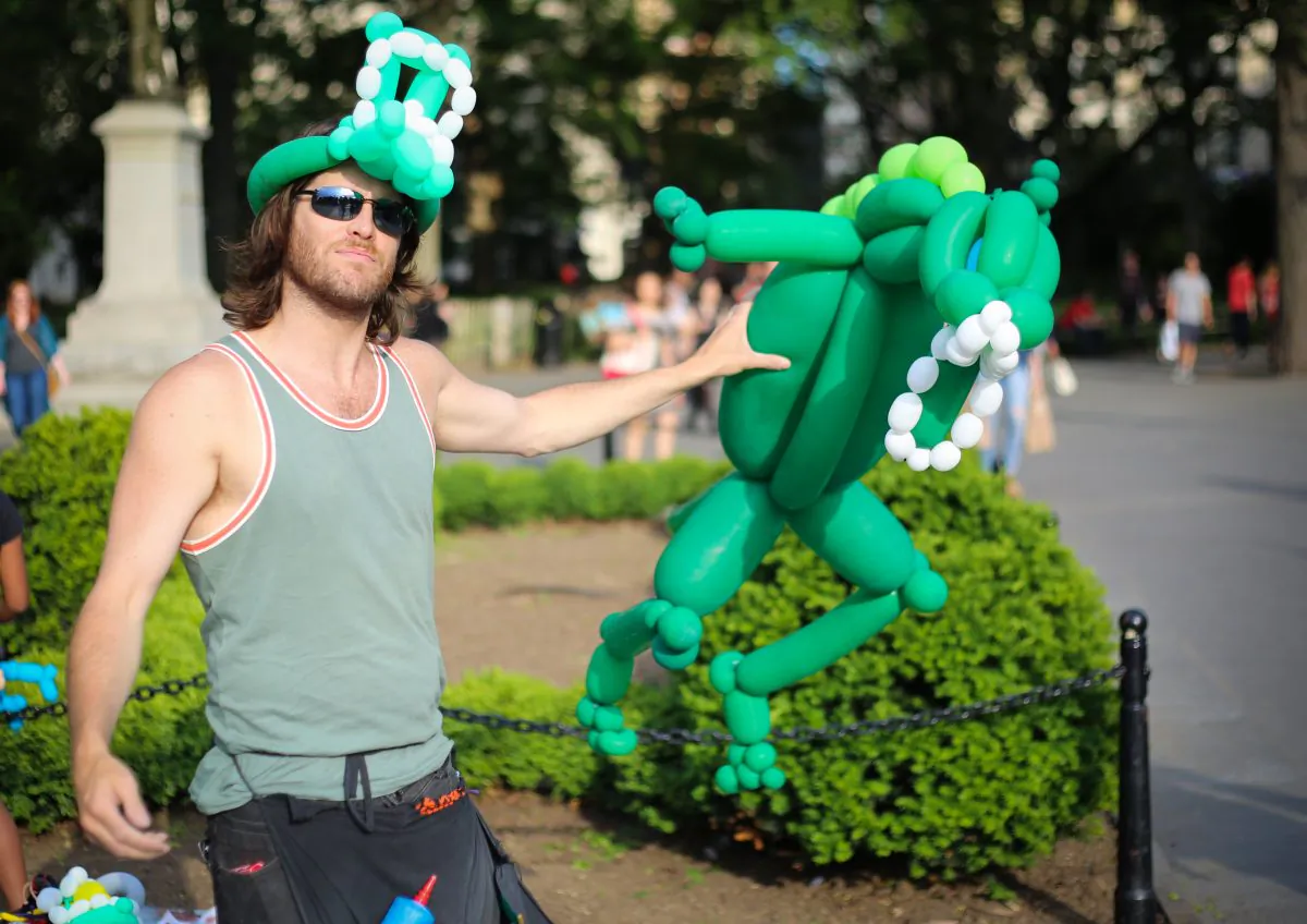 John Murdock holds a Godzilla made of several balloons tied ogether in Washington Square Park, New York City on May 30, 2014. (Benjamin Chasteen/Epoch Times)