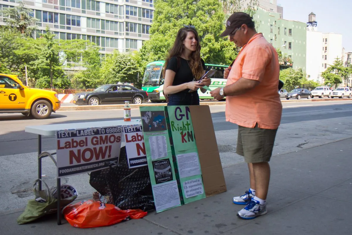 A woman from New York Public Interest Research Group speaks to a passerby about the potential dangers of GMOs in front of a Whole Foods Market in the Lower East Side, New York, on June 3, 2014. (Jonathan Zhou/Epoch Times)