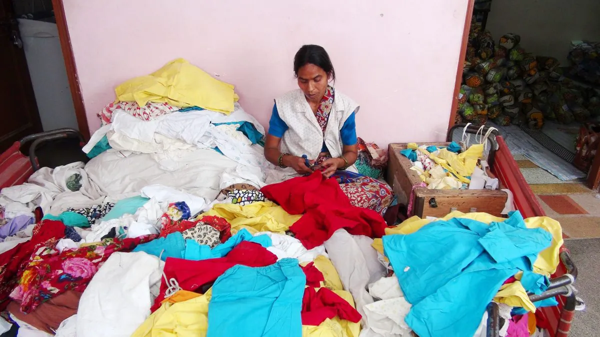 An employee of Indian NGO Goonj sits amid discarded and sorted clothes at the organization’s office in New Delhi on June 7, 2014. Goonj collects, washes, and mends discarded clothes and uses them as currency to pay poor villagers to build community infrastructure, an initiative called Clothes for Work. (Venus Upadhayaya/Epoch Times)