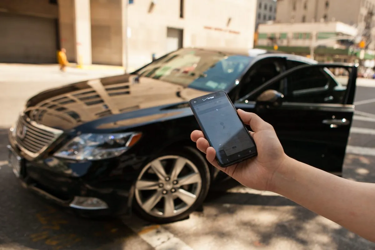 A person holds out his smartphone displaying the Uber app, before getting in a black Lexus which was hailed using the app, in Manhattan, on June 8, 2014. (Benjamin Chasteen/Epoch Times)