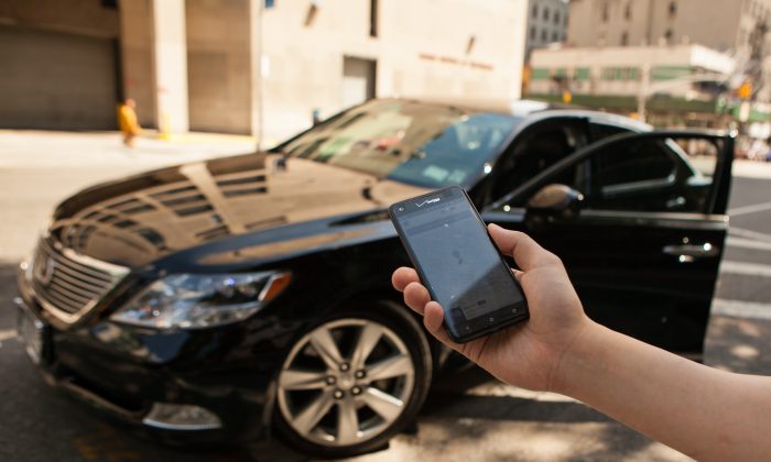 A person holds out his smartphone displaying the Uber app, before getting in a  black Lexus which was hailed using the app, in Manhattan, on June 8, 2014. (Benjamin Chasteen/Epoch Times)