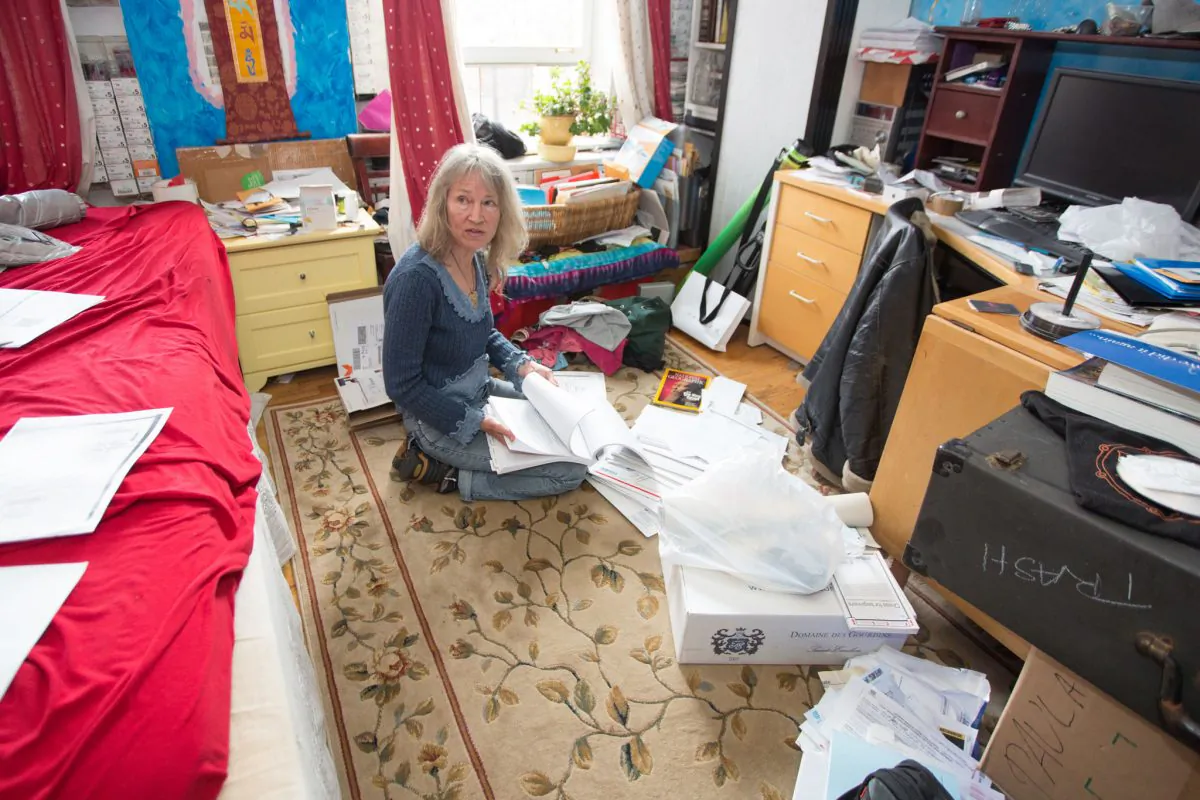Paula Gloria Tsaconas Barton sifting through court documents and letters in her Gramercy Park South co-op studio, June 11, 2014. Last year, while she was travelling, Tsaconas Barton got notice her apartment had been sold to someone else and is now facing eviction. (Laura Cooksey/Epoch Times)