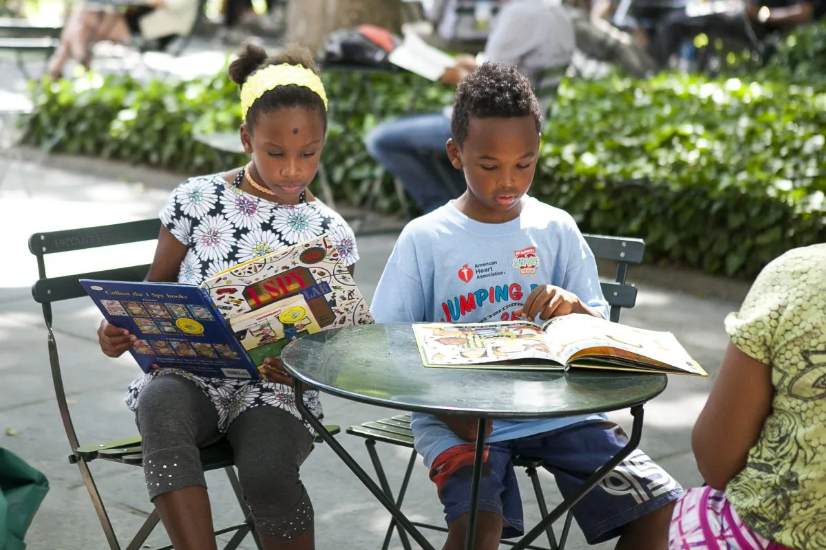 Two kids read at the Bryant Park Reading Room, in Manhattan, on June 25, 2014. (Samira Bouaou/Epoch Times)