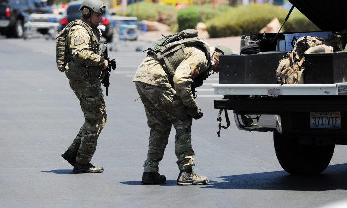 Las Vegas police officers prepare to go near the scene of a shooting in Las Vegas, Sunday, June 8, 2014. The spree began around 11:30 a.m. Sunday when a man and woman walked into CiCi's Pizza and shot two officers who were eating lunch, Las Vegas police spokesman Larry Hadfield said. (AP Photo/Las Vegas Review-Journal, Eric Verduzco)