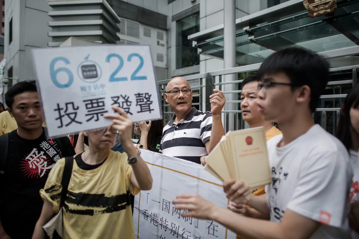 A demonstrator supporting the Occupy Central movement holds a placard asking residents to cast ballots for the June 22 referendum on three proposals outlining rules for the chief executive election, during a protest outside Beijing's representative office in Hong Kong on June 11, 2014. A website associated with that referendum was recently hacked. (Philippe Lopez/AFP/Getty Images)
