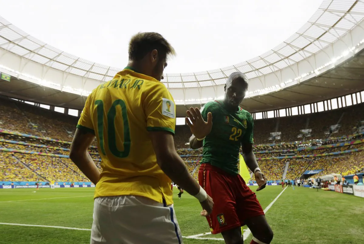 Cameroon's Allan Nyom tries to shake hands with Brazil's Neymar after pushing him to the ground in the corner during the group A World Cup soccer match between Cameroon and Brazil at the Estadio Nacional in Brasilia, Brazil, Monday, June 23, 2014. (AP Photo/Natacha Pisarenko)