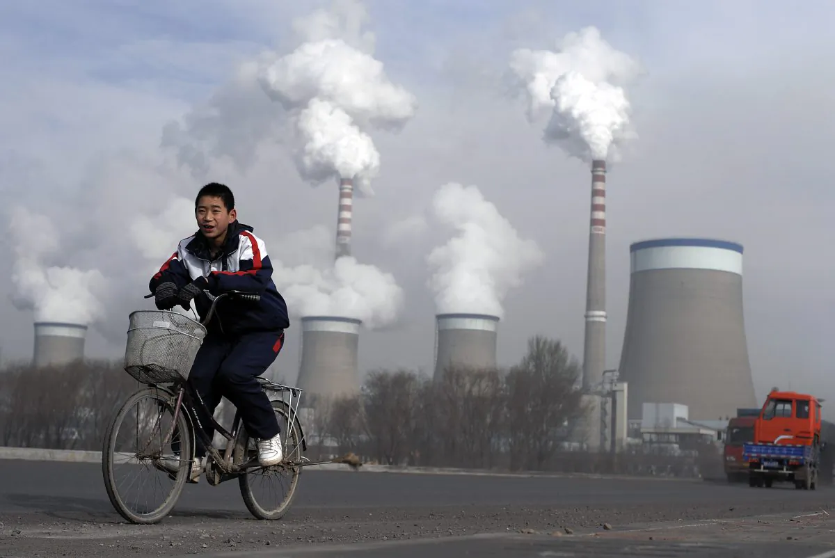 A Chinese boy cycles past a cooling towers of a coal-fired power plant in Dadong, Shanxi Province, China, on Dec. 3, 2009. (Andy Wong/AP)